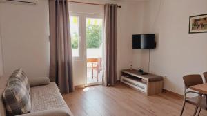 a living room with a couch and a table and a window at Apartments Nikola Caska in Novalja