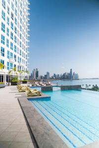 a swimming pool with lounge chairs and a large building at private ocean view studio apartment in Panama City