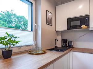 a kitchen with a counter with a sink and a window at VacationClub – Sosnowa 4 Apartament 25 in Mielno
