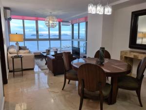 a dining room with a table and chairs and a living room at Amplio y hermoso apartamento frente a la bahía. in Panama City