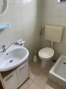 a bathroom with a white toilet and a sink at Apartment Enna in Kaštela