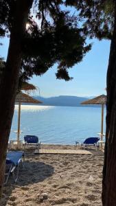 a beach with two chairs and umbrellas and the water at Seaside pearl in Lygia