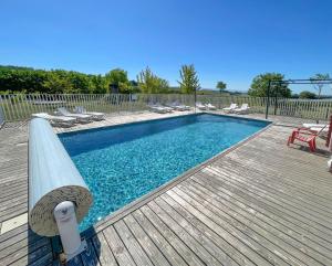 a swimming pool on a wooden deck with chairs at Ferme Robin in Marsaz
