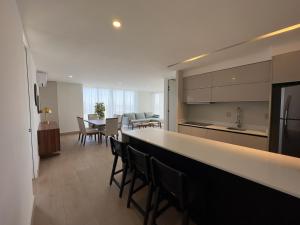 a kitchen and living room with a counter and chairs at frente al malecón, 5 min zona dorada by G P S rentas in Mazatlán
