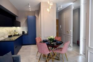 a kitchen and dining room with a table and pink chairs at CoCo Elite Apartments Zator in Zator