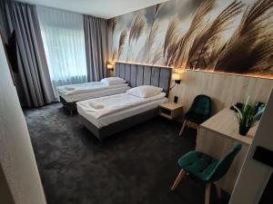 a hotel room with two beds and a green chair at Nowe M4 Żyrardów Centrum - blisko Suntago in Żyrardów