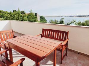 a wooden table and two chairs on a balcony at Apartments Nikola Caska in Novalja
