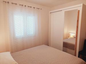 a bedroom with a mirror and a bed and a window at Apartments Nikola Caska in Novalja