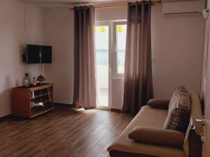a living room with a couch and a sliding glass door at Apartments Nikola Caska in Novalja