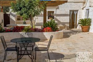 un patio con tavolo, sedie e fiori di Cycas a Cisternino