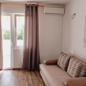 a living room with a couch and a window at Apartments Nikola Caska in Novalja