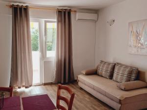 a living room with a couch and a window at Apartments Nikola Caska in Novalja