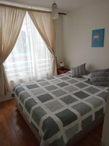 1 dormitorio con 1 cama con manta a cuadros en Departamento, Apartamento económico en La Serena, en La Serena