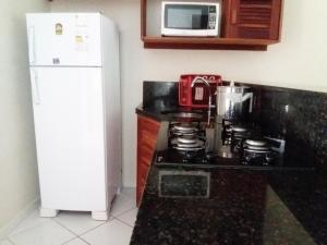a kitchen with a stove and a refrigerator and a microwave at Pipa Brisas do Amor in Pipa