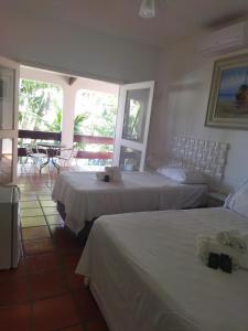 1 dormitorio con 2 camas, mesa y sillas en Pousada Chez Soleil CibrateI Itanhaém, en Itanhaém