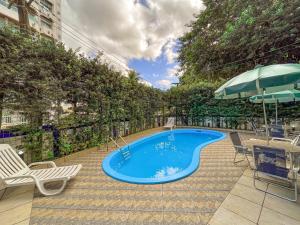 a swimming pool with chairs and an umbrella at Hotel Nacional Inn Guarujá in Guarujá