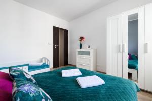 een slaapkamer met een groen bed met 2 handdoeken erop bij Przestronny apartament Centrum między 2 jeziorami in Olsztyn