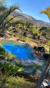 a large pool of blue water with palm trees at Pousada Cachoeira do Sol in Jaboticatubas