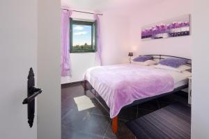 a bedroom with a bed with purple sheets and a window at Villa Niko Your vacation starts here in Rudine