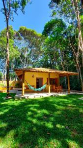 una pequeña casa amarilla con una hamaca en un patio en Vila dos Macacos Trancoso en Trancoso