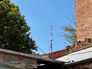 an old brick building with a tv tower in the background at Apartment in old TBILISI in Tbilisi City