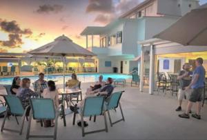 um grupo de pessoas sentadas numa mesa perto de uma piscina em Castle Villas at Bluebeards by Capital Vacations em Charlotte Amalie