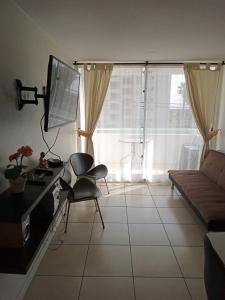 a living room with a couch and a table and a television at Departamento, Apartamento económico en La Serena in La Serena