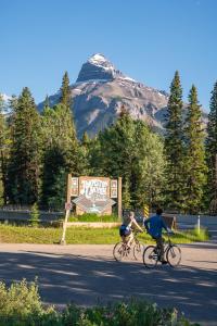two people riding bikes down a road with a mountain in the background at Johnston Canyon Lodge & Bungalows in Castle Junction