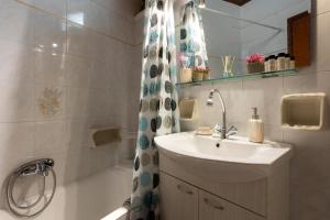 bagno con lavandino e doccia con vasca di Nature Village Apartment ad Ágioi Déka