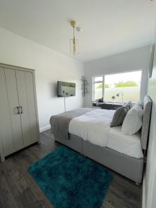 a white bedroom with a large bed and a window at Isabella Rooms in Hockley