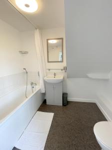 a bathroom with a sink and a tub and a toilet at Isabella Rooms in Hockley