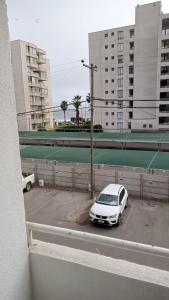 un coche blanco estacionado en un estacionamiento con edificios en Departamento, Apartamento económico en La Serena, en La Serena