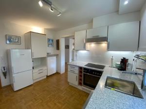 uma grande cozinha com electrodomésticos brancos e pisos em madeira em ALB 74 em Waldbronn