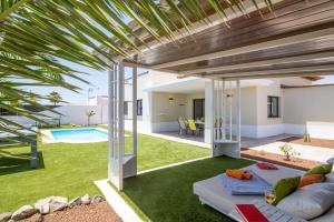 an open living room with a patio and a pool at Villa Caleta Heights by Villa Plus in Caleta De Fuste