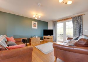 a living room with two couches and a flat screen tv at Llys Bach in Llanarmon