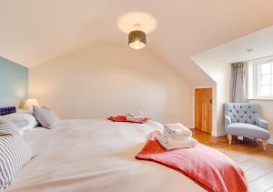 a bedroom with a large white bed and a chair at Llys Bach in Llanarmon