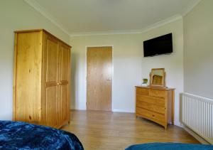 1 dormitorio con 1 cama, vestidor y TV en Skipjack Field View en Ingworth