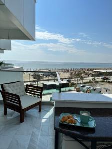 a table with a plate of food on a balcony overlooking the beach at Jo Residence Mamaia Nord in Mamaia Nord