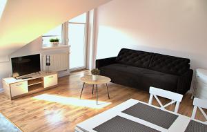 a living room with a black couch and a table at Apartament Ogrodowa in Mrągowo