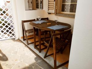una mesa de madera y sillas con copas de vino. en Summer Room- Fronte Spiaggia, en La Caletta