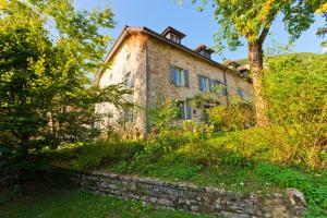 an old stone house on a hill with trees at A l'Ombre du Château in Nans-sous-Sainte-Anne