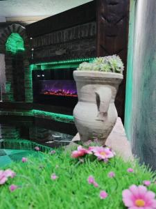 un jarrón de piedra con flores frente a una chimenea en Vila N&N Palace en Bistriţa Bîrgăului
