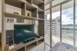 uma sala de estar com uma televisão grande e uma janela grande em Flat Completo na Ponte Estaiada SP em São Paulo