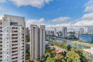 Cette chambre offre une vue sur une ville avec de grands bâtiments et une rivière. dans l'établissement Flat Completo na Ponte Estaiada SP, à São Paulo