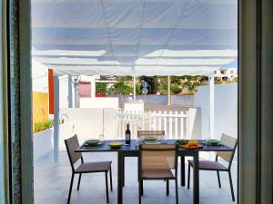un patio con tavolo da pranzo e sedie sotto una tenda bianca. di Da Mimma di Casa Camilla Journey a Marina di Pescoluse