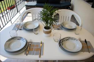 a table with plates and glasses and a plant on it at Olivemare Holidays in Nea Irakleia