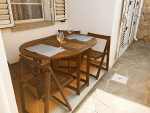 una mesa de madera y sillas con copas de vino. en Summer Room- Fronte Spiaggia, en La Caletta 25 fotos más