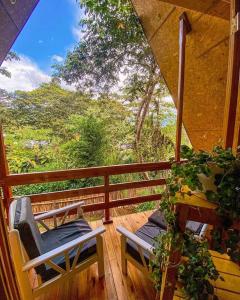 a porch with two chairs and a view of the forest at La casa del Erizo in Oxapampa