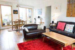 uma sala de estar com um sofá de couro preto e um tapete vermelho em Beautiful Rooftop between Paris and Versailles em Chaville