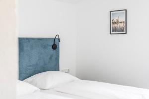 - une chambre avec un lit blanc et une tête de lit bleue dans l'établissement Rössle Appartement, à Bezau